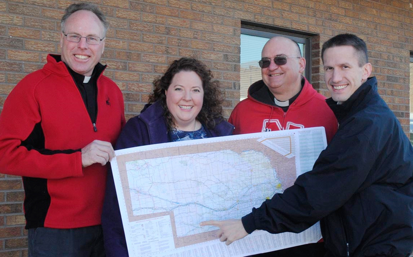 GRANT DEANERY - Priests of the Grant Deanery are excited to have hired Katie Dubas as Youth Director. Pointing out the area on the map she will serve are, from left, Fr. Thomas Kuffel, Katie Dubas, Fr. Bernard Lorenz and Fr. Lothar Gilde. Not pictured is Father Thomas Wiedel. (SNR photo by Jan Schultz)